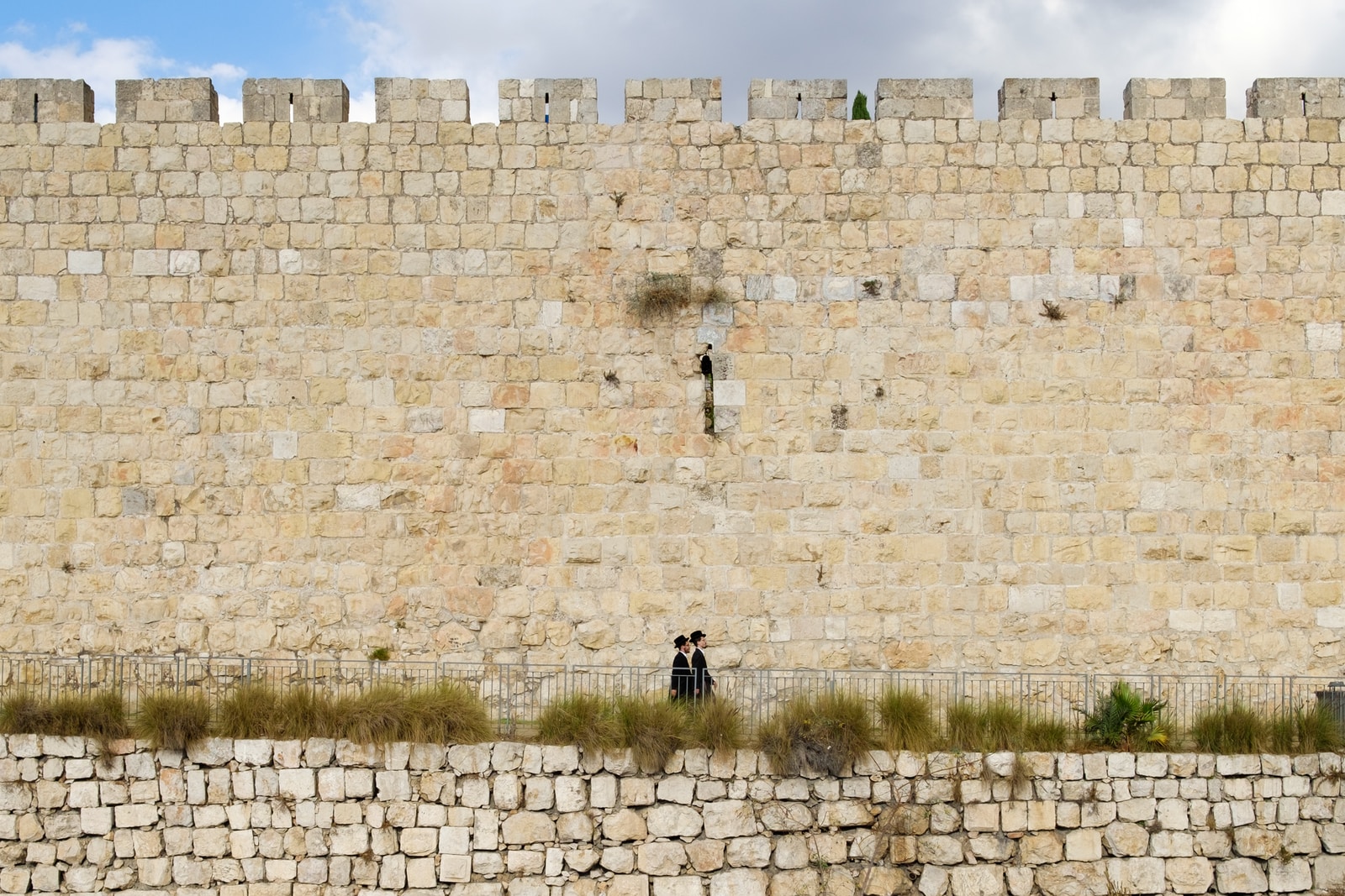 Photo by Arno Smit two person walking beside beige brick wall