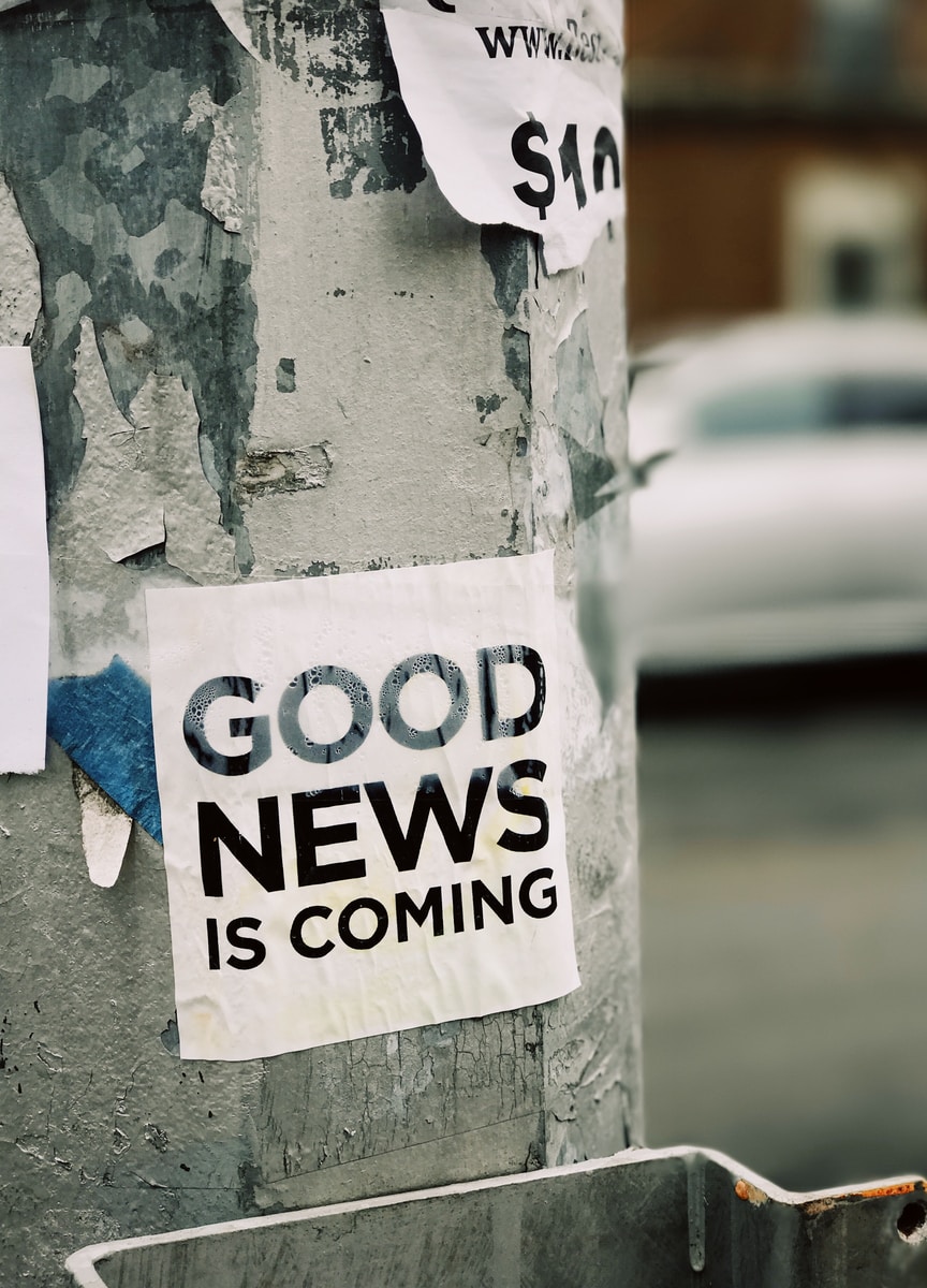 Photo by Jon Tyson white Good News Is Coming paper on wall