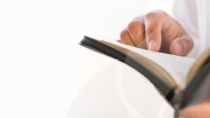 Hands holding an open Bible with white background