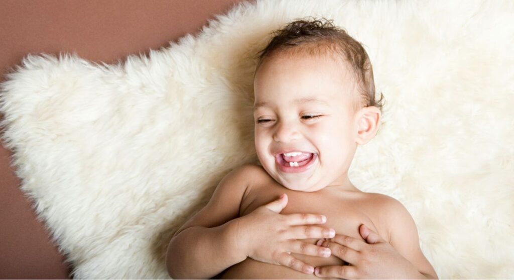 boy laughing while lying on sheepskin rug