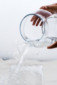 person holding clear glass jar with water