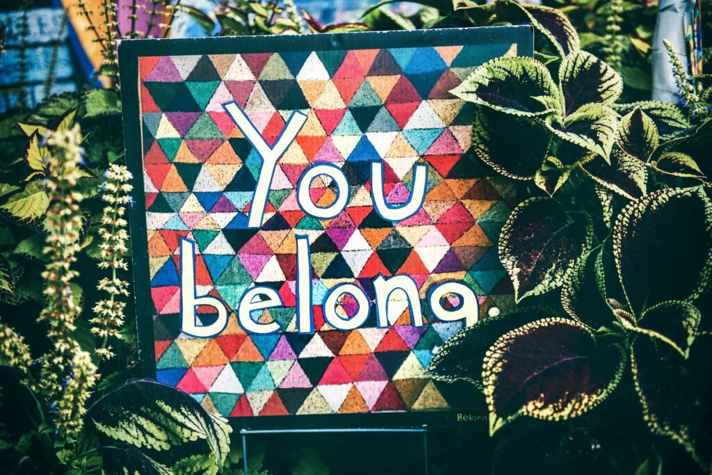 a sign that says You Belong surrounded by plants